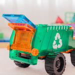 Toy dump truck picking up a magnetic tile with a recycling symbol on a blurred background of colourful blocks
