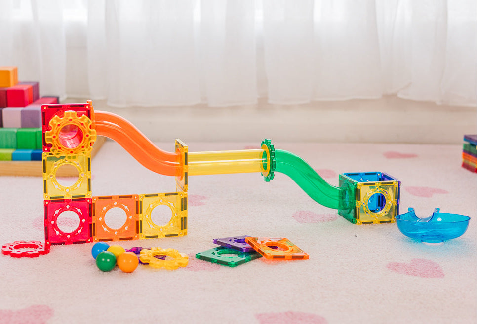 Rainbow coloured ball run in light filled playroom