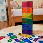Colourful magnetic tiles sitting as a tow on a rug.