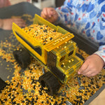 Magnetic tile dump truck filled with corn kernels on a tray