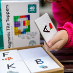 Child holding a uppercase A tile topper from pack of learn & grow toys tile toppers